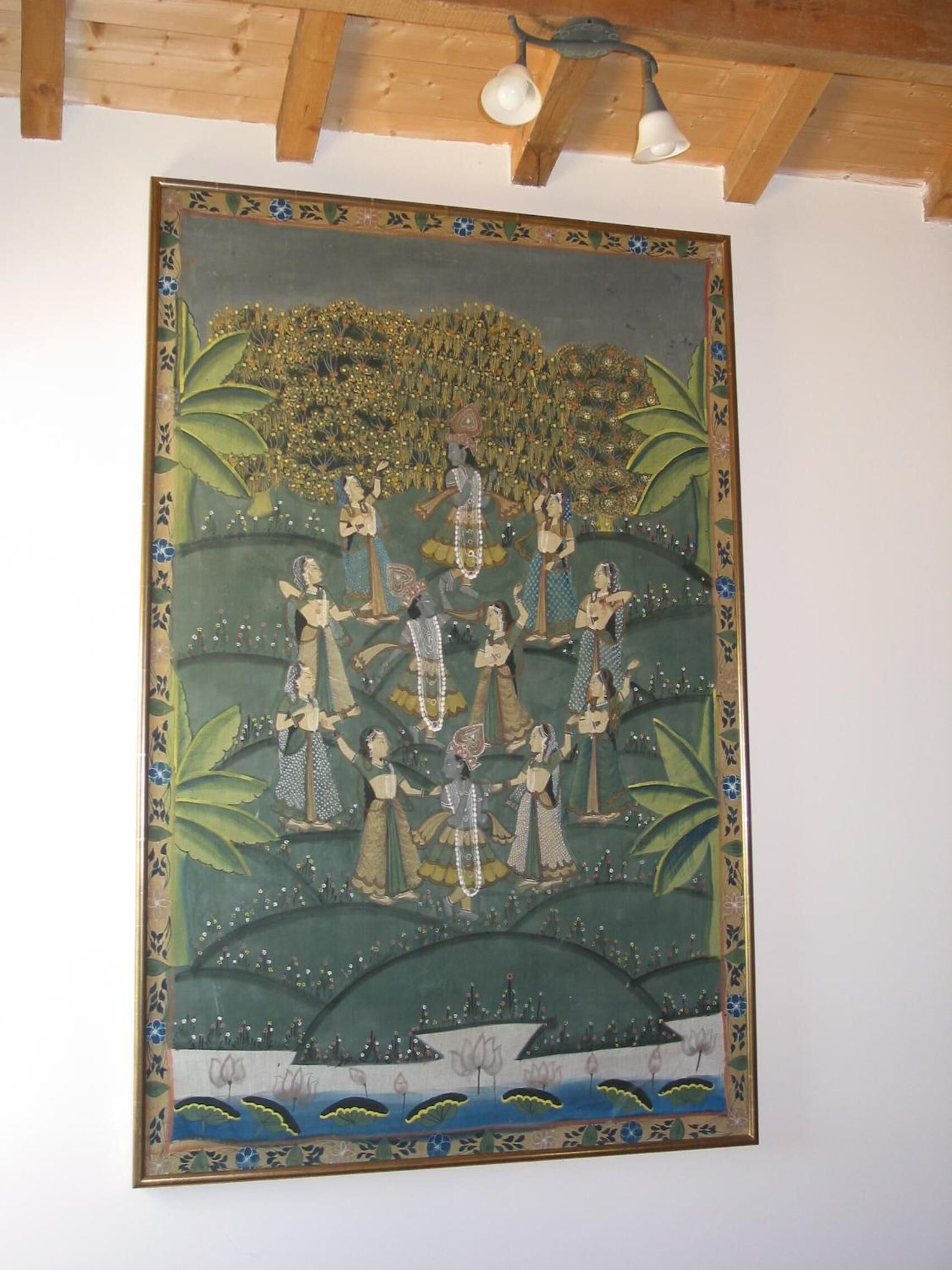 A framed artwork depicting a traditional scene with multiple figures and a lotus pond.