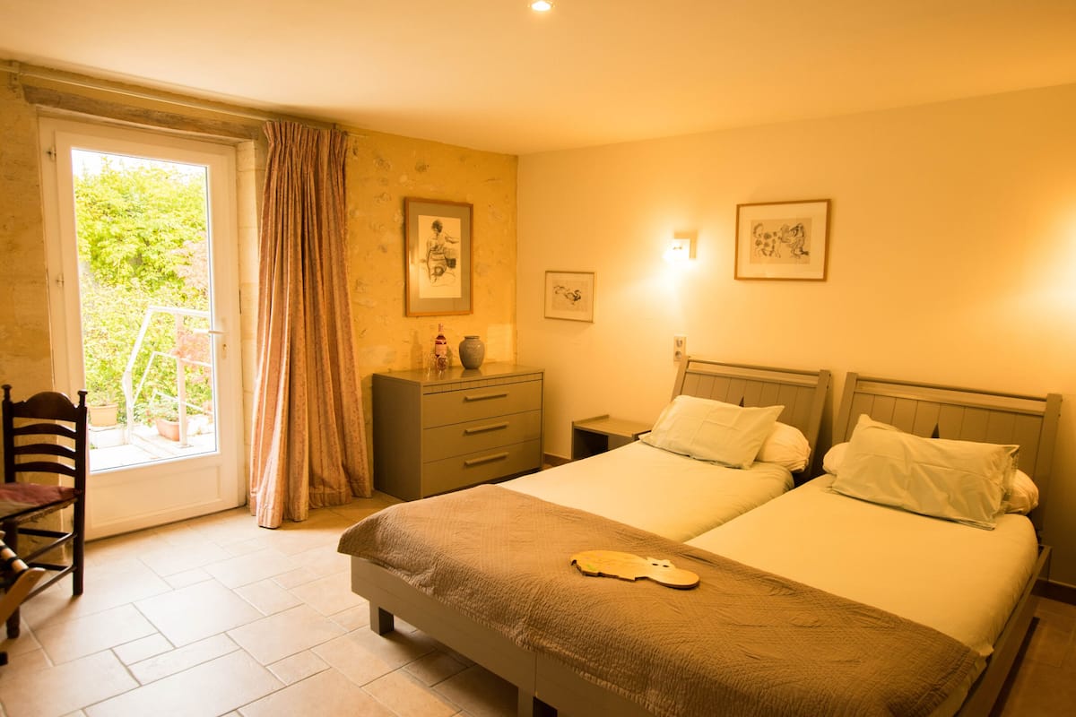 Un dormitorio con dos camas, una silla, un tocador y una ventana con cortinas.