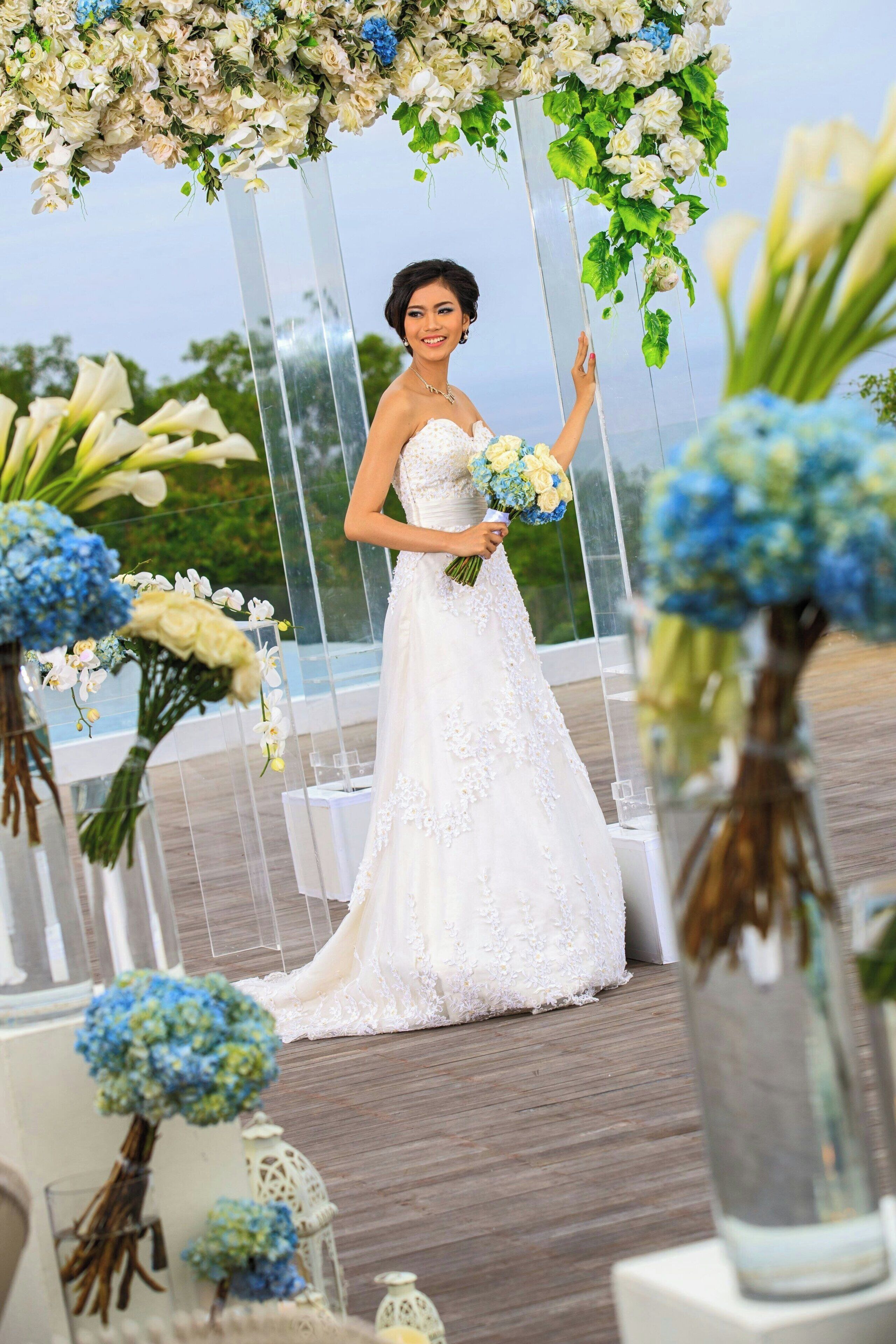 Una ceremonia de boda con una novia en un vestido blanco, sosteniendo un ramo, bajo un arco floral.