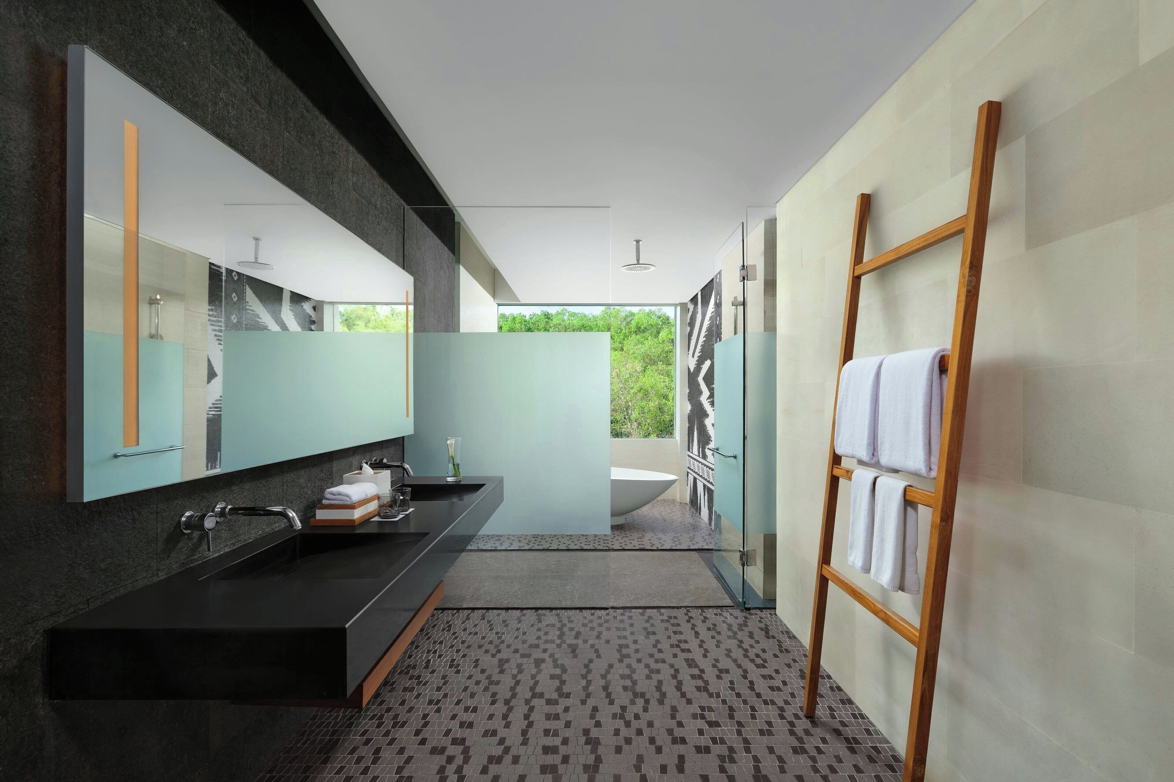 A modern bathroom with a black sink, a large mirror, and a wooden towel rack.