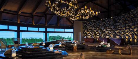 A spacious lobby with a large chandelier, seating areas, and a geometric wall design.