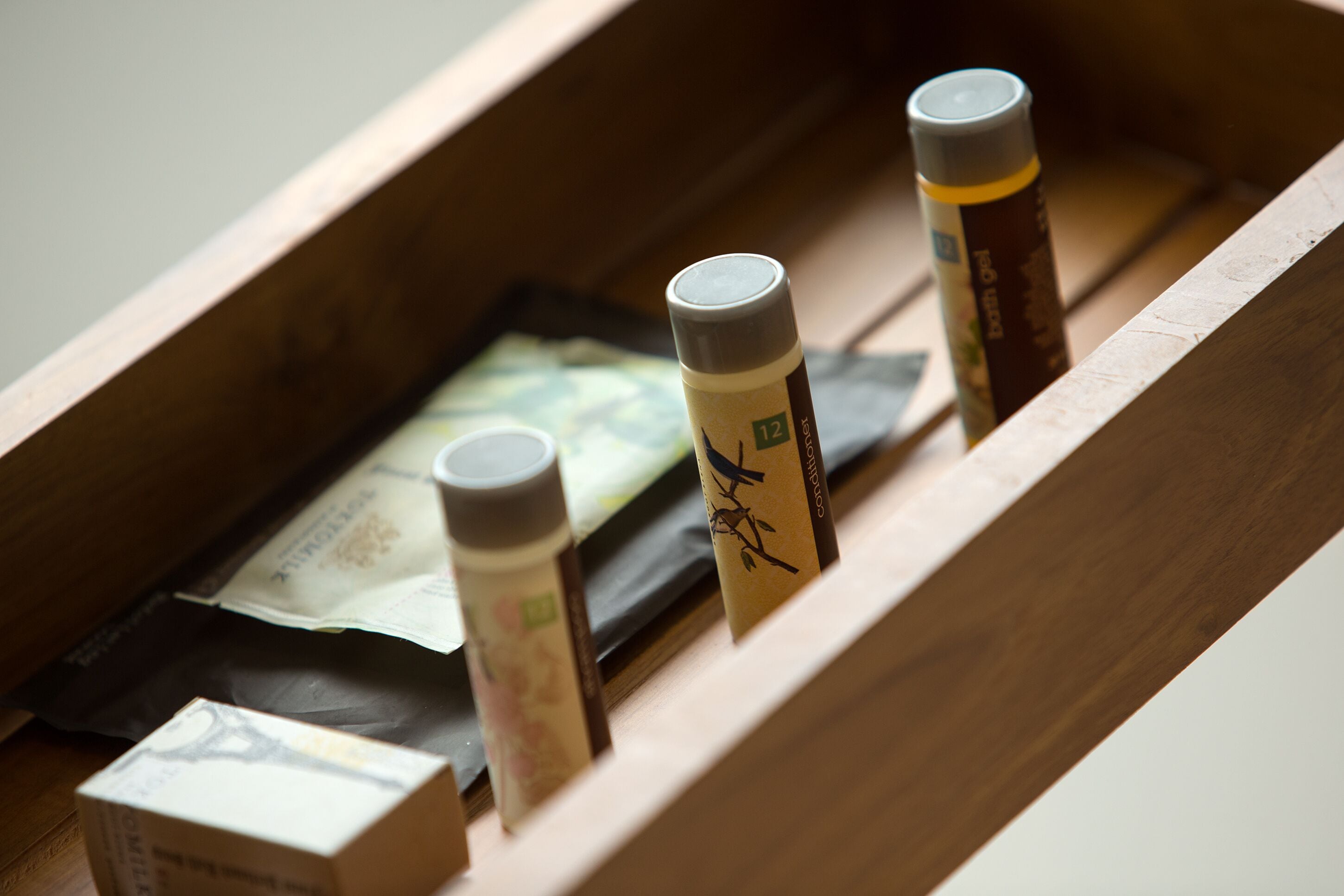 A wooden drawer containing various items including a bottle, a small box, and a packet.