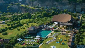 A resort with a swimming pool, lounge chairs, and a thatched-roof building. - Renaissance Bali Uluwatu Resort & Spa (Ungasan)