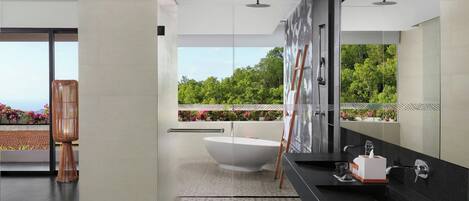 Une salle de bain moderne avec une baignoire sur pieds, un grand miroir et une vue sur la verdure environnante.