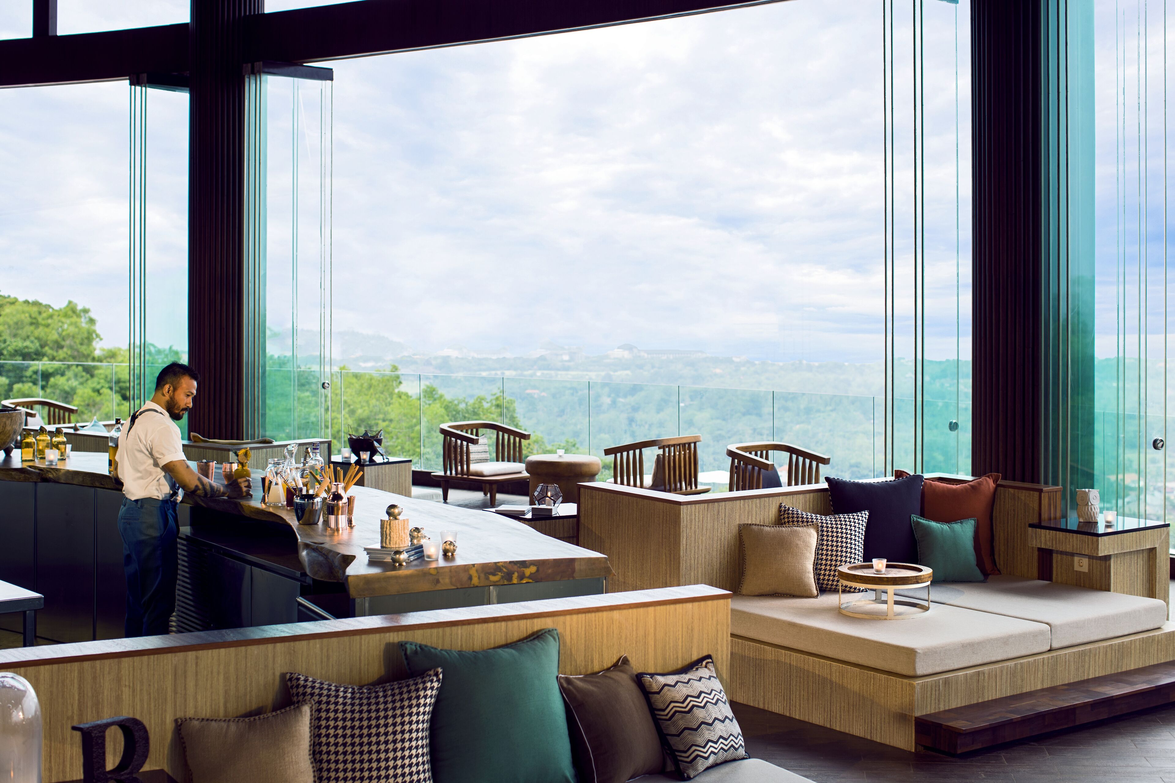 Un espace bar moderne offrant une vue sur le paysage grâce à de grandes fenêtres.