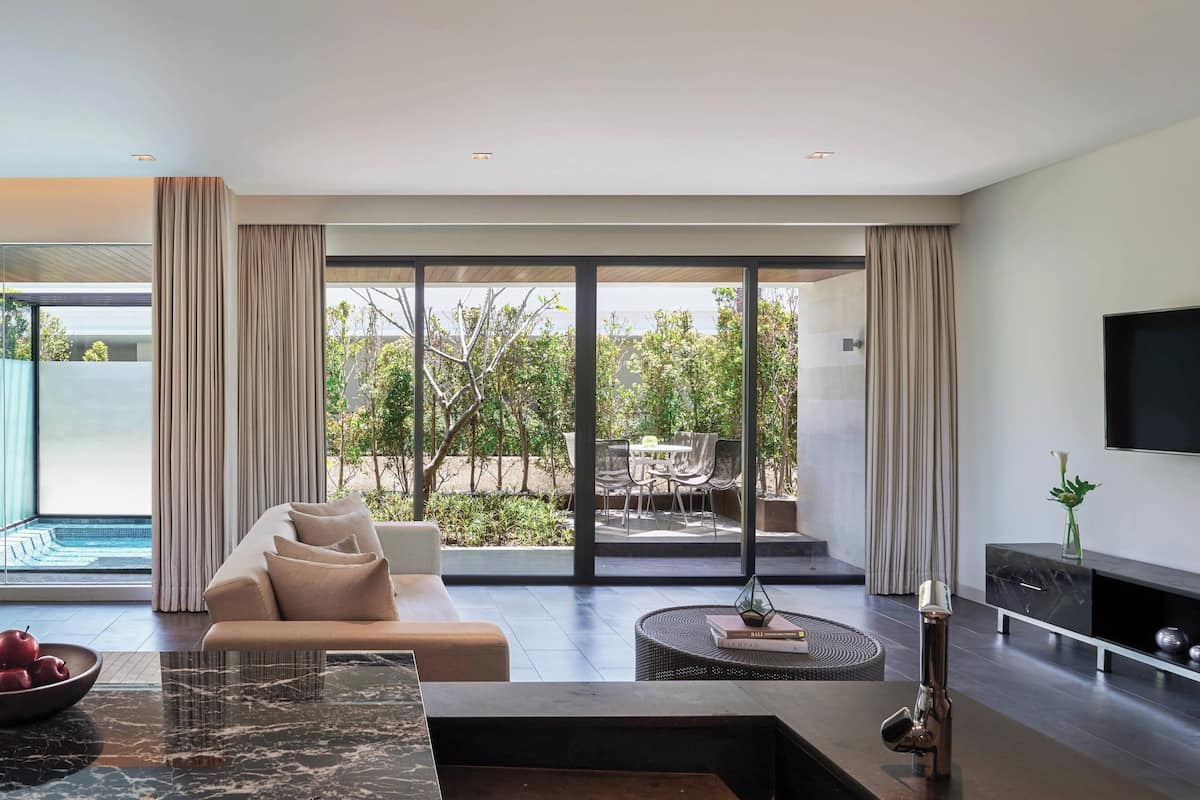 A modern living room with a sofa, coffee table, and a TV on the wall.