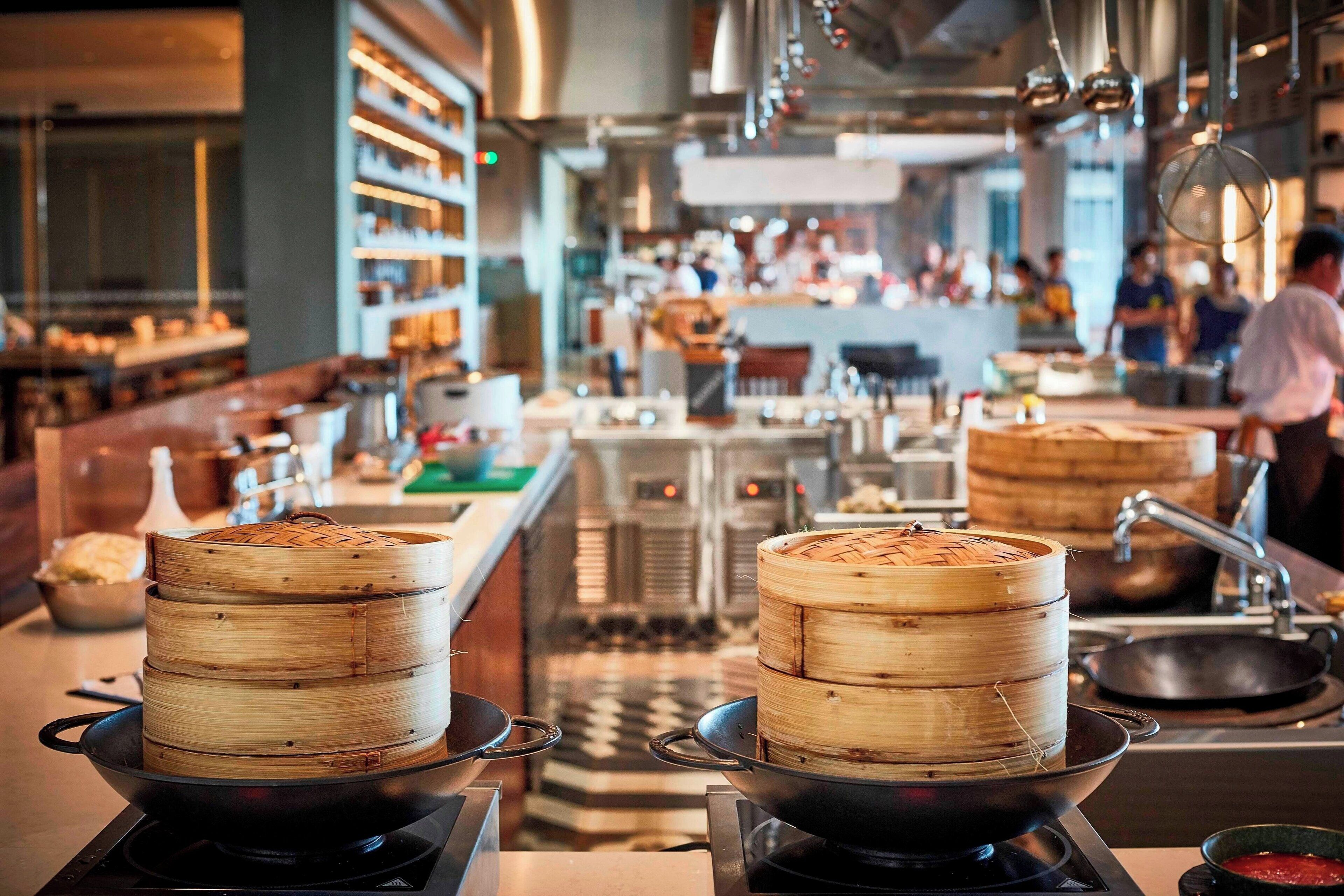 A kitchen with bamboo steamers on a stove, a sink, and a counter with various kitchen items.