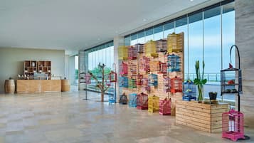 A spacious lobby with a large window, a reception desk, and a wall decorated with colorful birdcages.