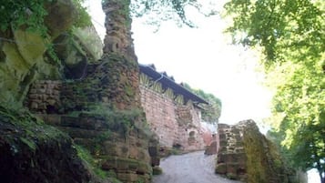 A narrow, unpaved path leading through a historic stone structure with overgrown vegetation.