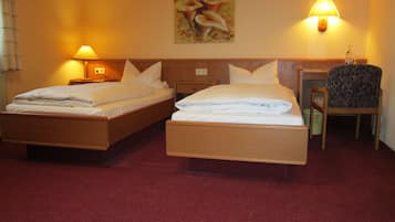 A hotel room with two beds, a desk, a chair, and a painting on the wall.