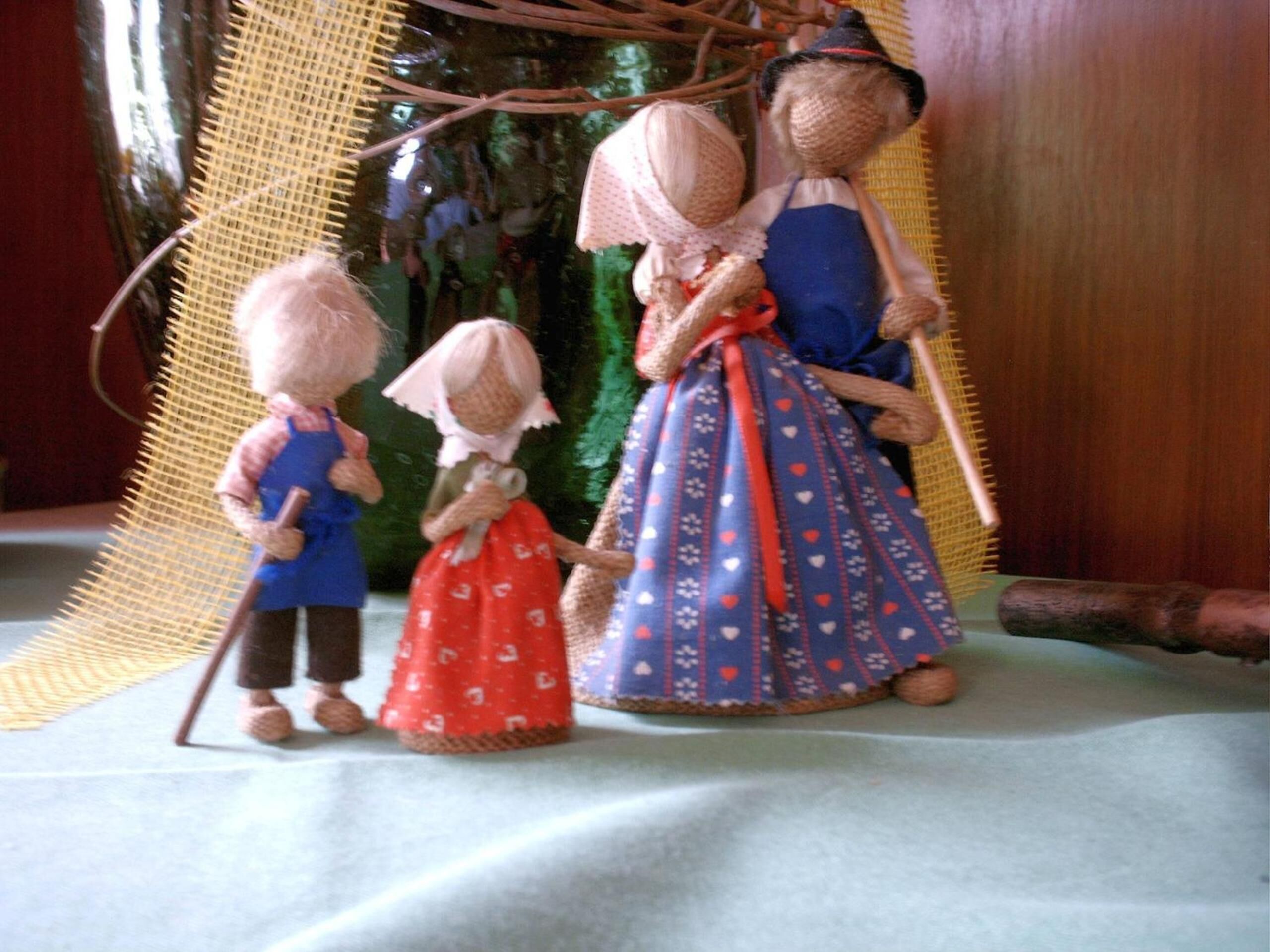 Three dolls dressed in traditional clothing, standing on a plain surface.