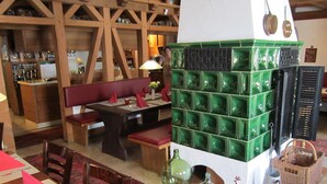 A restaurant interior with wooden beams, a green and white tiled wall, red cushioned seating, and a variety of table settings. - Gasthaus Neupert (Lemberg)