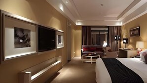 Une chambre d’hôtel moderne dotée d’un grand lit, d’une télévision à écran plat, d’un canapé, d’un bureau et d’une chaise.