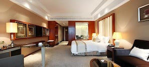 Een hotelkamer met een bed, bureau, stoel, bank en een grote spiegel.