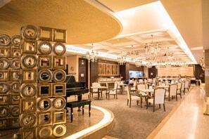 A spacious hotel lobby with a grand piano, elegant chandeliers, and a modern design. - Yihe Grand Hotel (Zhongshan)