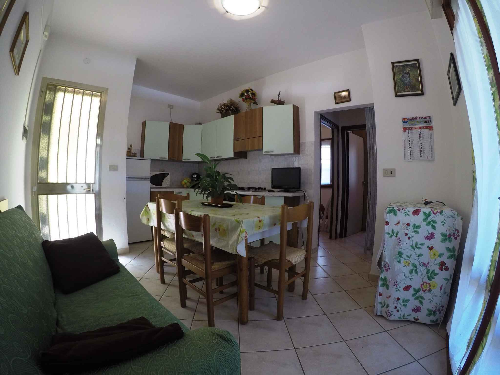 A compact living space with a dining area, kitchenette, and a green sofa.