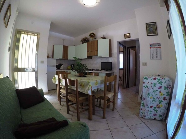 A compact living space with a dining area, kitchenette, and a green sofa.