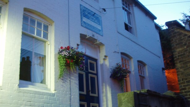 A white building with a blue door and windows, some flower boxes, and a brick staircase. - Stoneway Guest House (Bridgnorth)