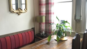 A dining area with a wooden table, red cushioned bench, and two chairs. A potted plant is on the table. - Stoneway Guest House (Bridgnorth)