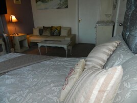 A hotel room with a bed, a small table, a sofa, and a TV.