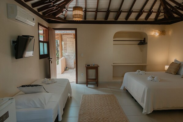 A room with two beds, a TV, a small table, and a ceiling fan.