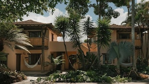 Un bâtiment à deux étages doté d’une piscine, entouré de plantes tropicales et de palmiers.