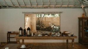 Un coin repas avec une table en bois mise pour le petit-déjeuner, comprenant des machines à café, des assiettes et des bols.