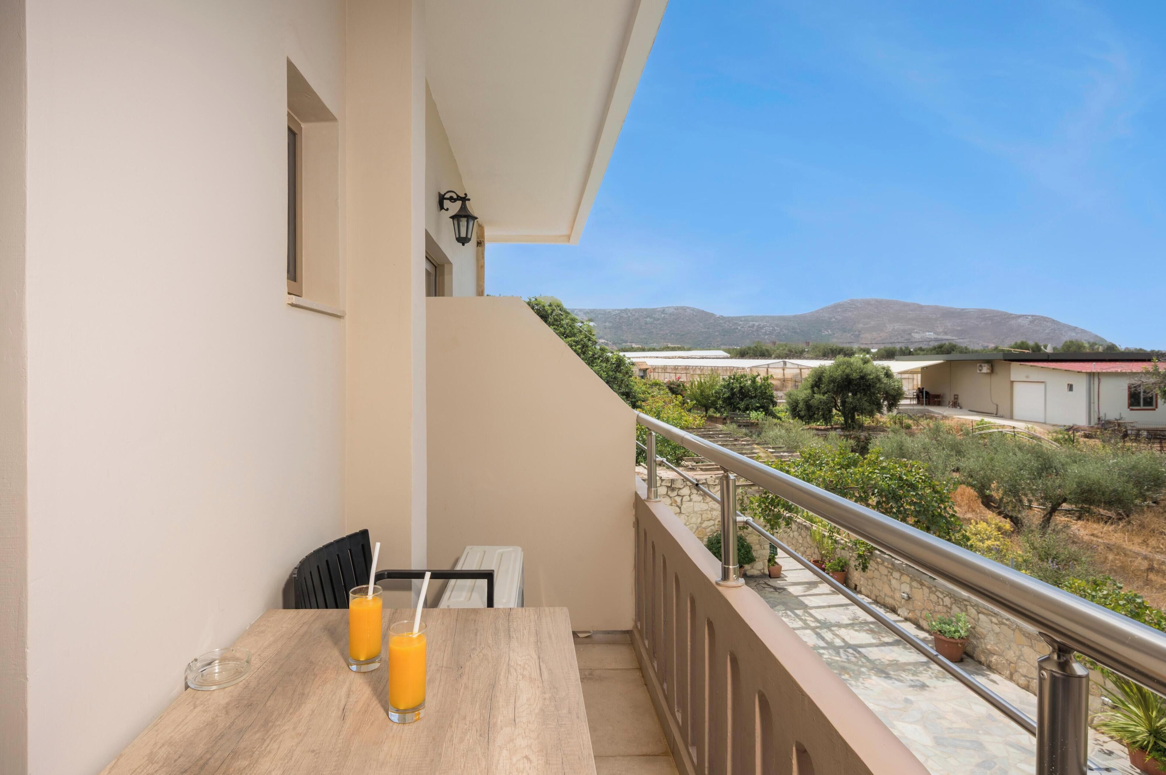 A balcony with a table, two chairs, and a glass of orange juice.