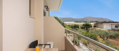 A balcony with a table, two chairs, and a glass of orange juice.