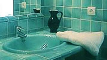 A bathroom with a sink, a mirror, and a black pitcher on the counter.