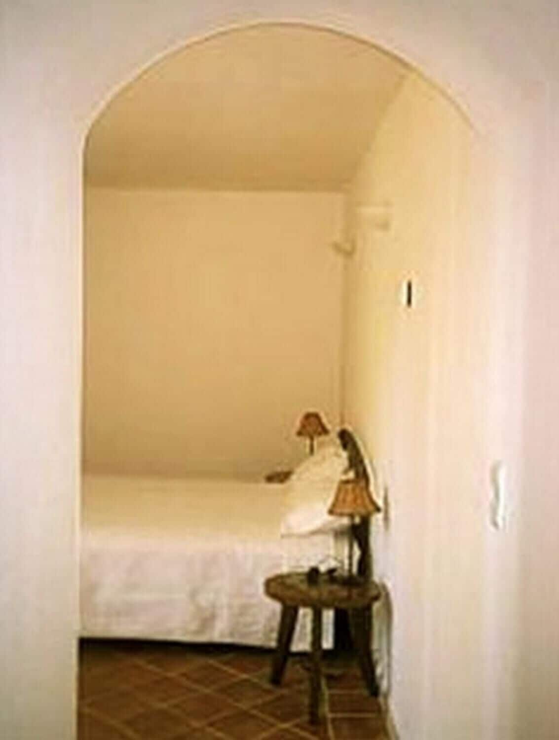 A room with a bed, a chair, and a lamp.