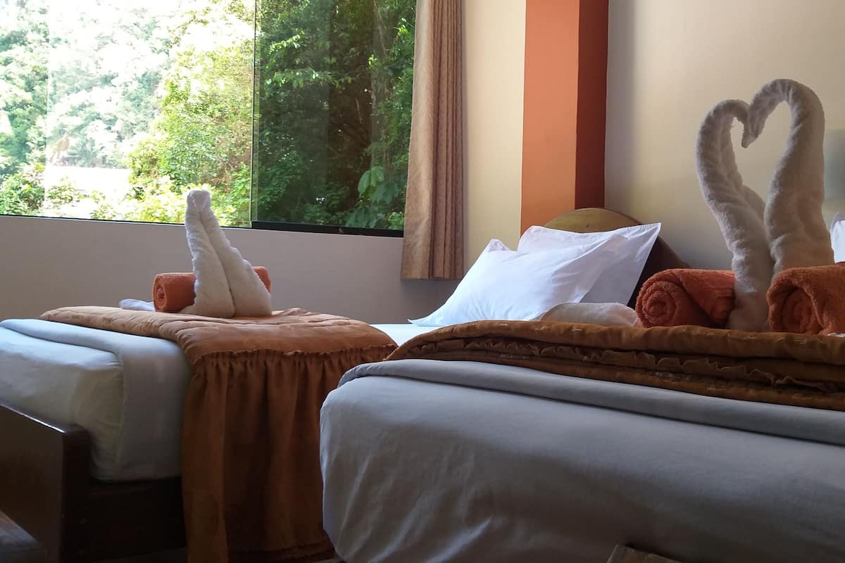 Une chambre d’hôtel avec deux lits, chacun agrémenté d’une serviette en forme de cœur et d’une serviette roulée posée sur la tête de lit.
