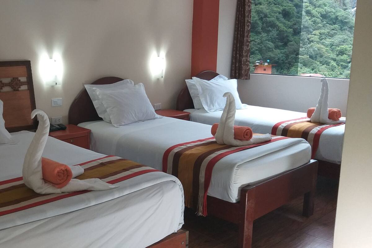 Une chambre d’hôtel avec trois lits, chacun agrémenté d’une serviette en forme de cygne.