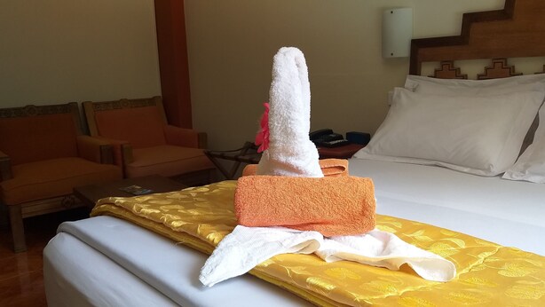 A hotel room with a bed, two chairs, a bedside table with a phone, and a wall-mounted light. - Hostal Vista Waynapata (Machu Picchu)