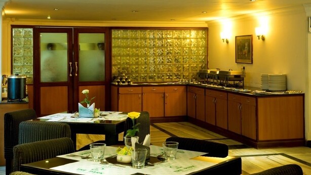 Een restaurantgedeelte in een hotel, met houten kasten, een glazen scheiding en een gedekte tafel.