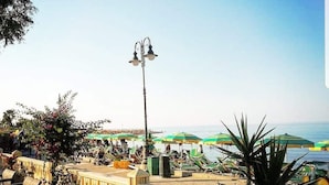 A beachfront patio with outdoor seating, a street lamp, and umbrellas. - La Marina residence club (Pietrapaola)
