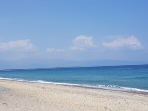 Une plage avec un ciel dégagé et une mer calme.