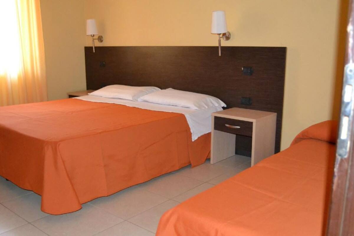 A hotel room with two beds, a wooden headboard, a nightstand, and a small table.