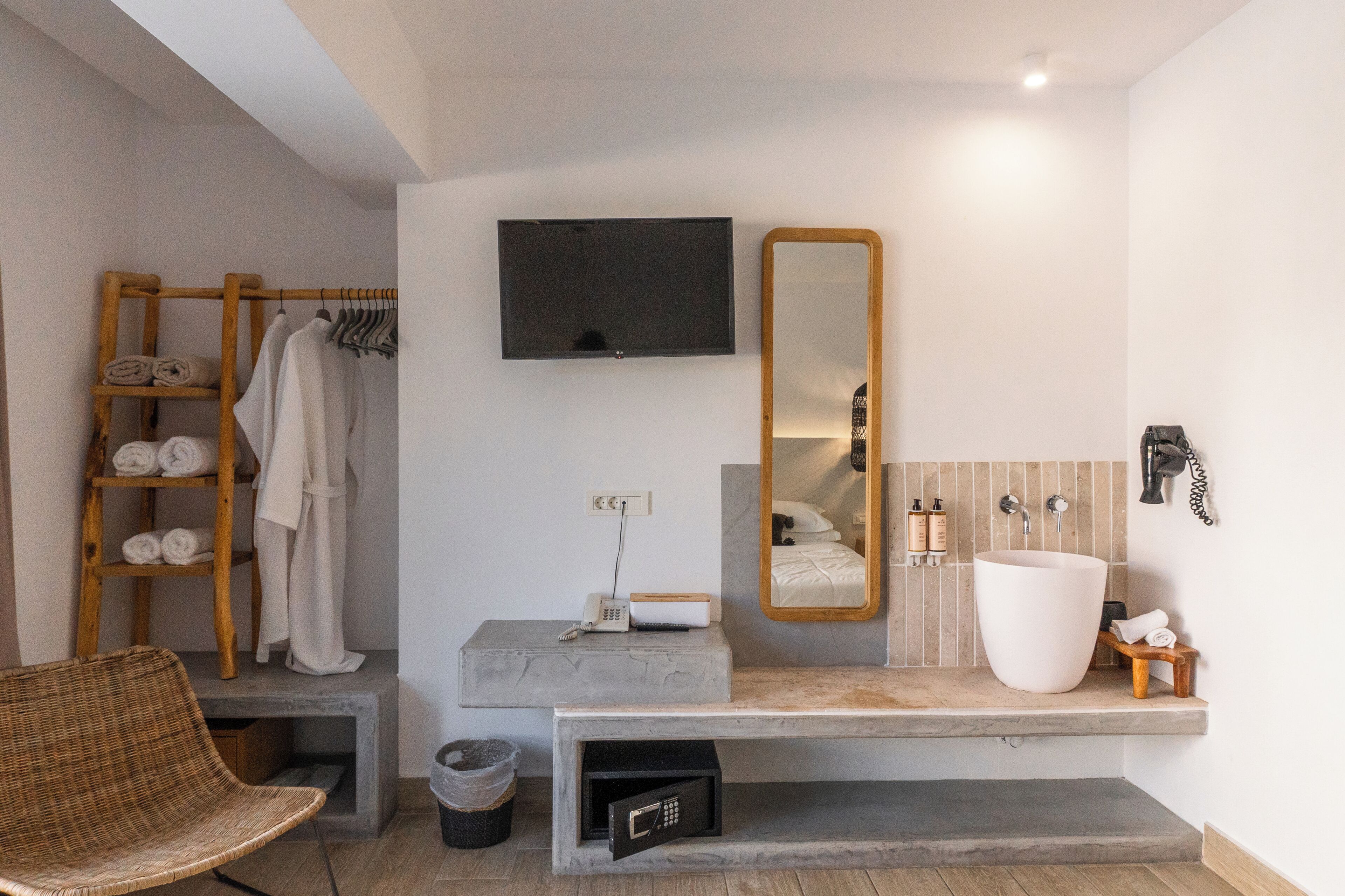 A modern bathroom with a large mirror, a vanity with a sink, and a wooden towel rack.
