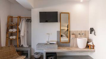 A modern bathroom with a large mirror, a vanity with a sink, and a wooden towel rack.