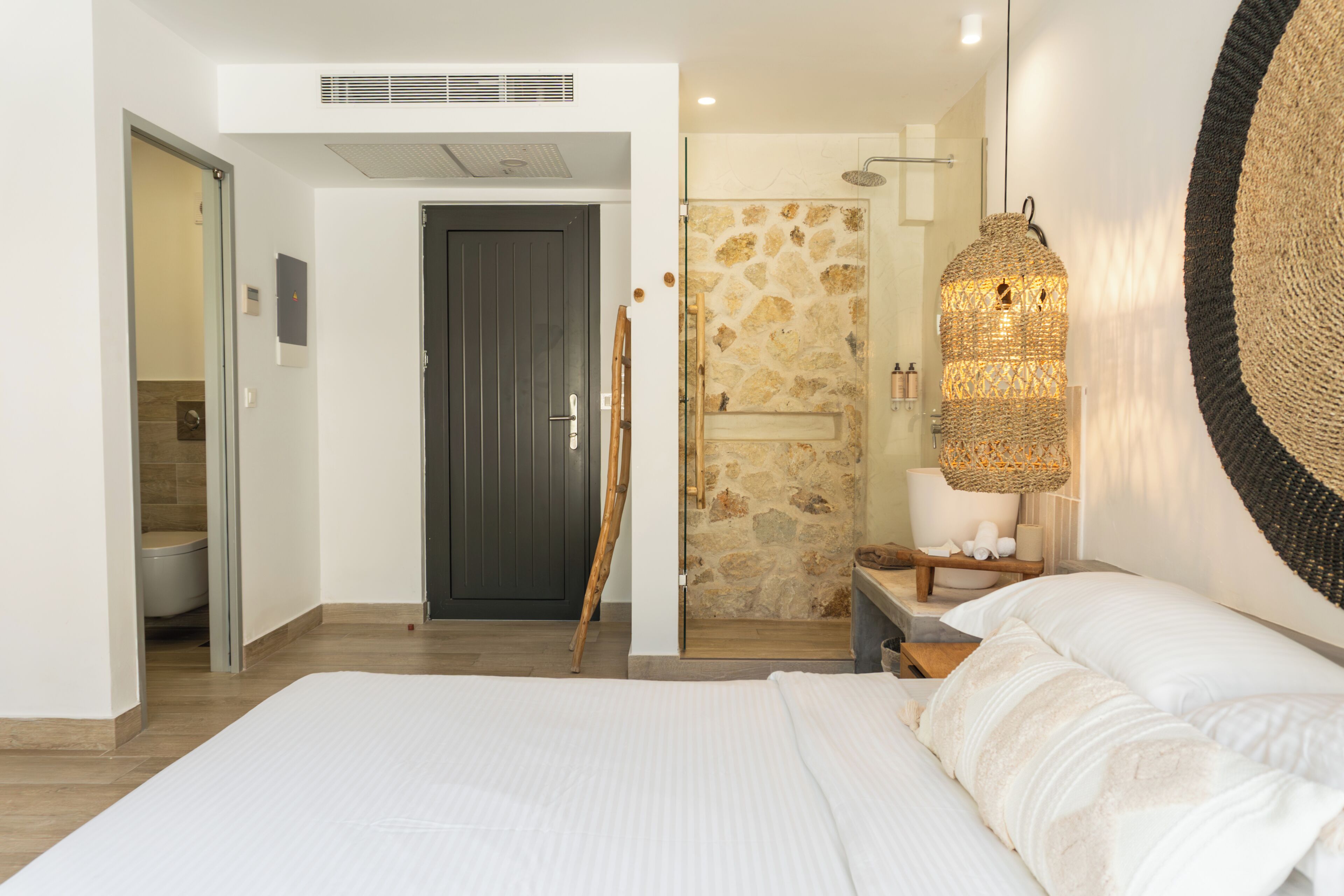 A modern bedroom with a large bed, a shower area, and a bathroom.