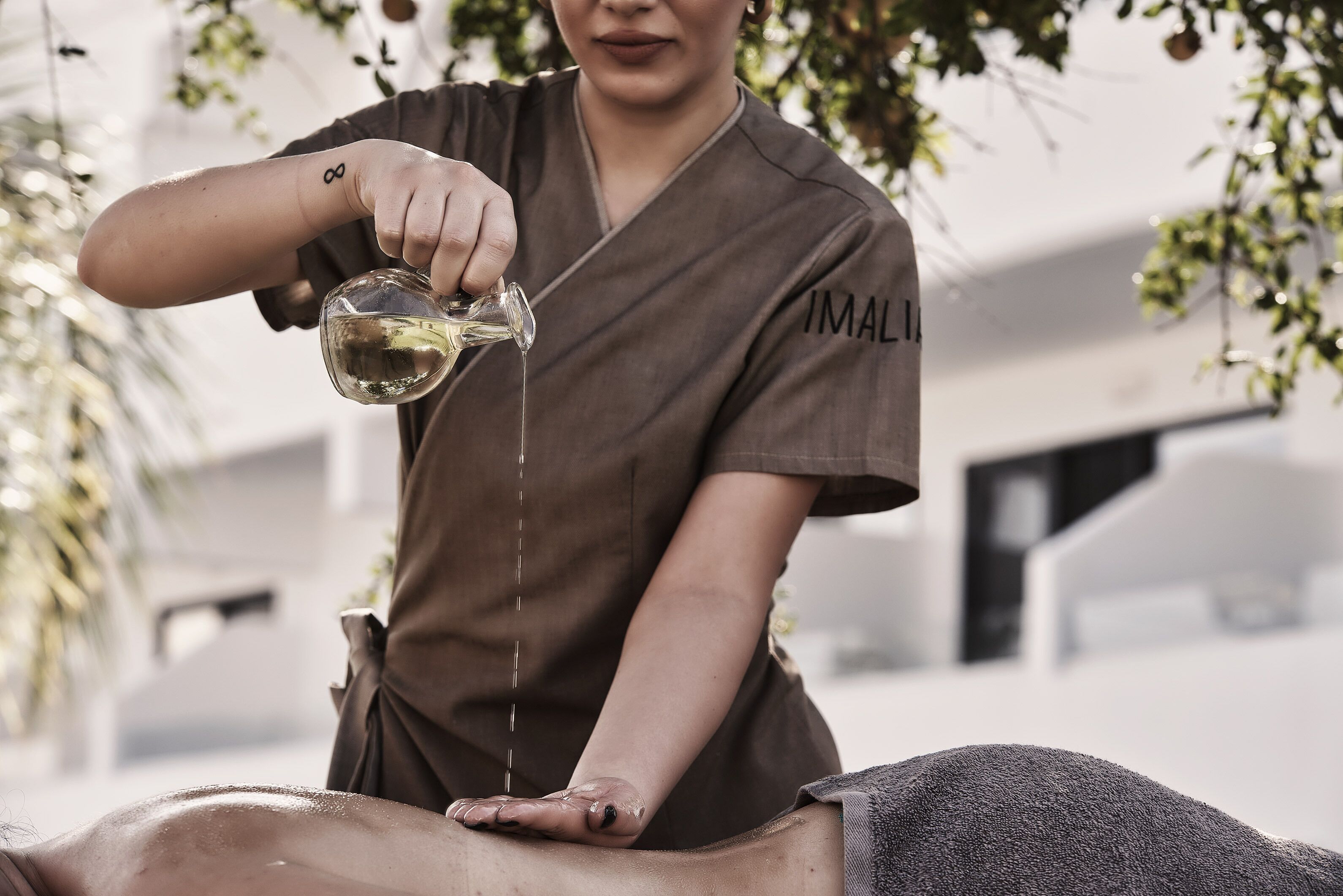 A person pouring a liquid onto another person's back.