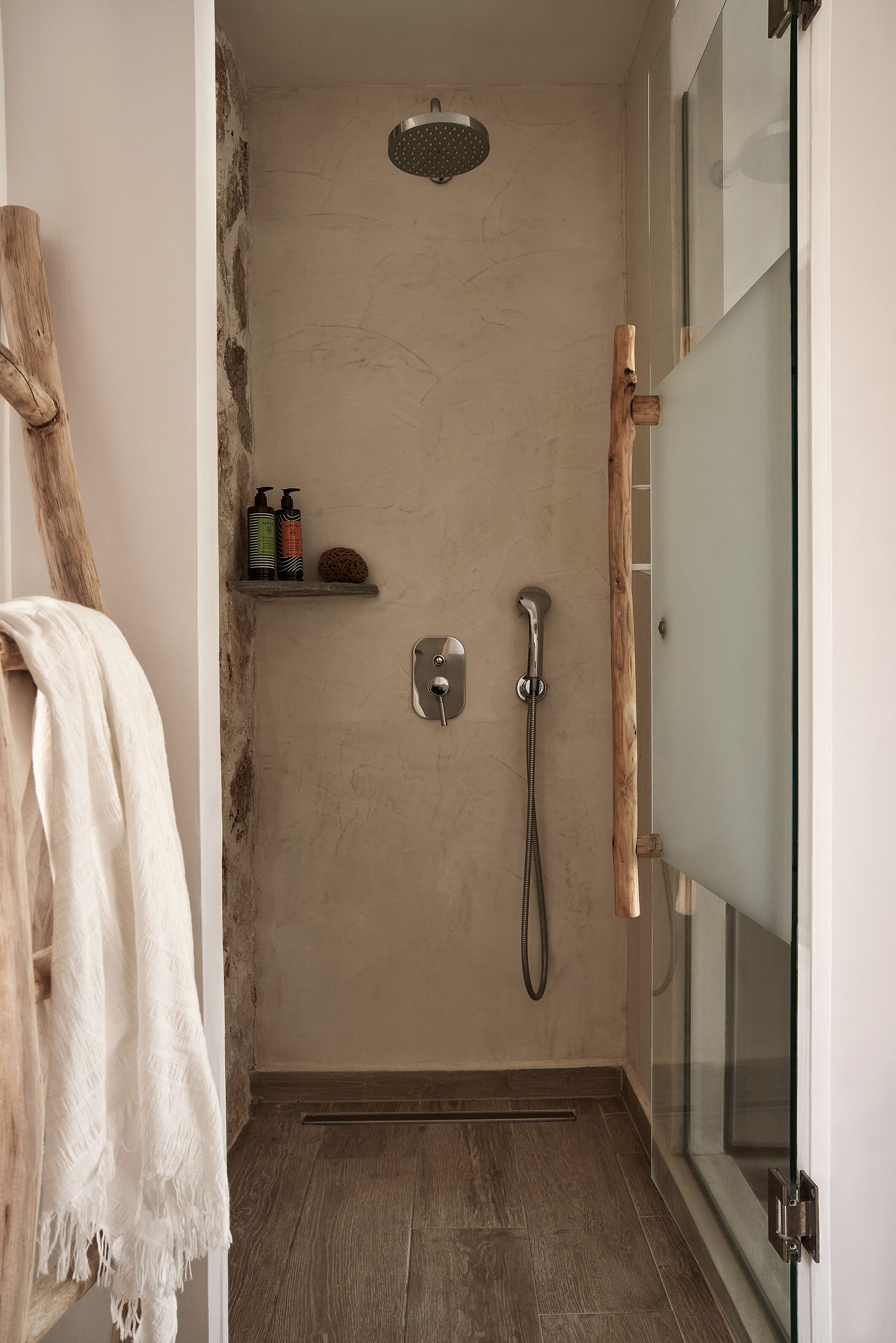 A bathroom with a shower, a towel rack, and a shelf with toiletries.