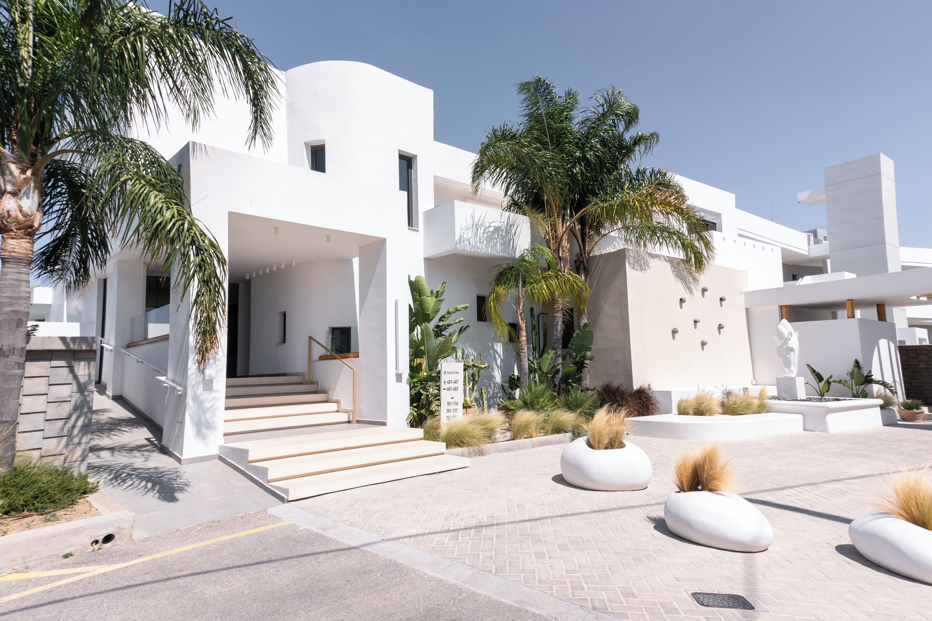 A modern building with a reception area, a staircase, and a landscaped courtyard with plants and seating areas.