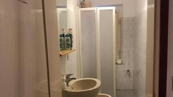 Une salle de bain avec un lavabo, deux toilettes, une douche et un miroir.