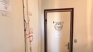 Un pasillo con una puerta que indica “Toilette” y un letrero con el nombre “Lucia” escrito en la pared.