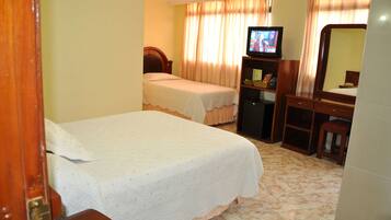 Habitación de hotel con dos camas individuales, televisión, escritorio con silla y espejo.