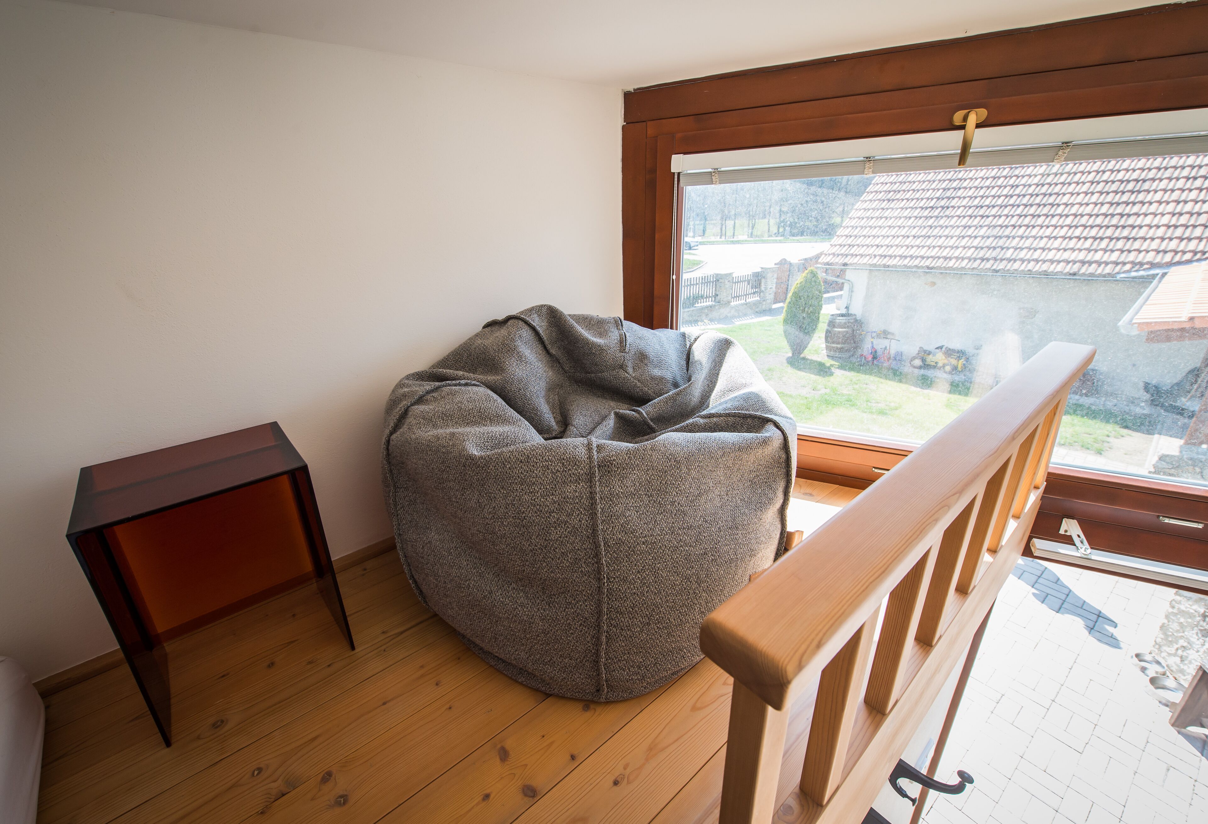 Ein Eckzimmer mit Sitzsack, kleinem Holztisch und Blick auf eine Wohngegend durch ein Fenster.
