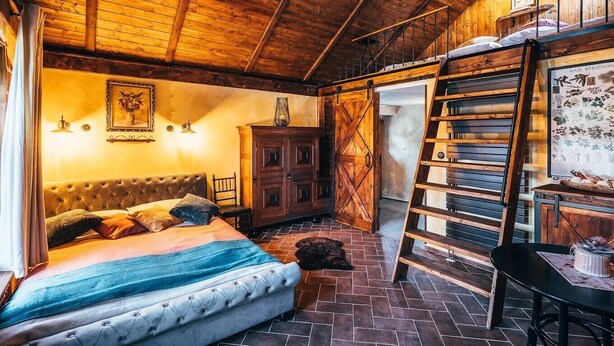 Un dormitorio rústico con cama, armario de madera, escalera y pared con estampado floral.