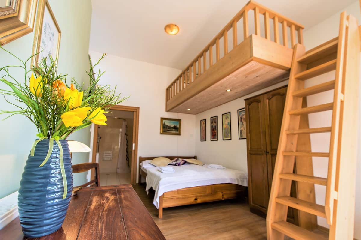 Quarto com beliche de madeira, escada de madeira, mesa de madeira e um vaso com flores amarelas.